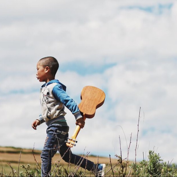 Child carrying ukulele.